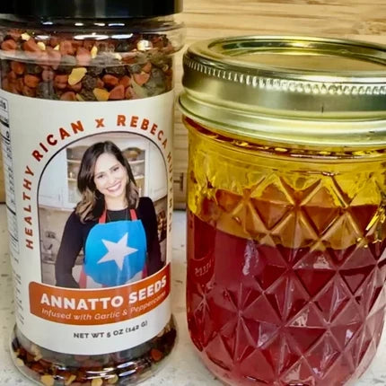 Annatto seeds beside a jar of Aceite de Achiote, the vibrant red-orange infused oil used to add color and flavor to Puerto Rican and Latin dishes.