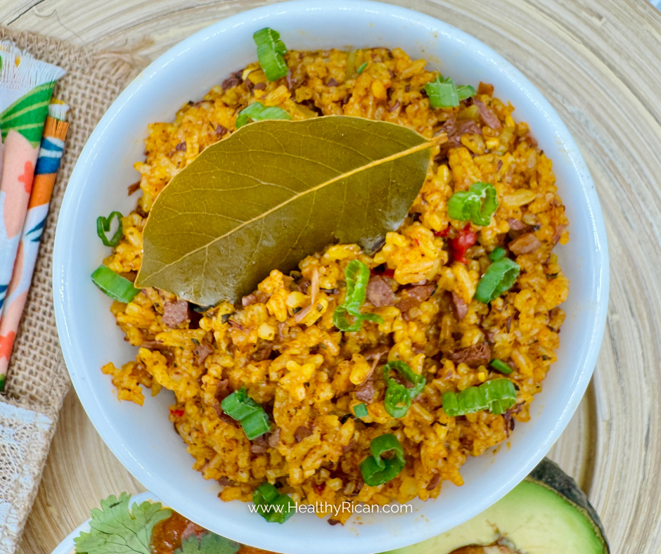 Arroz con Pollo served in a bowl with seasoned rice, tender chicken, green onions, and a bay leaf beside fresh avocado.