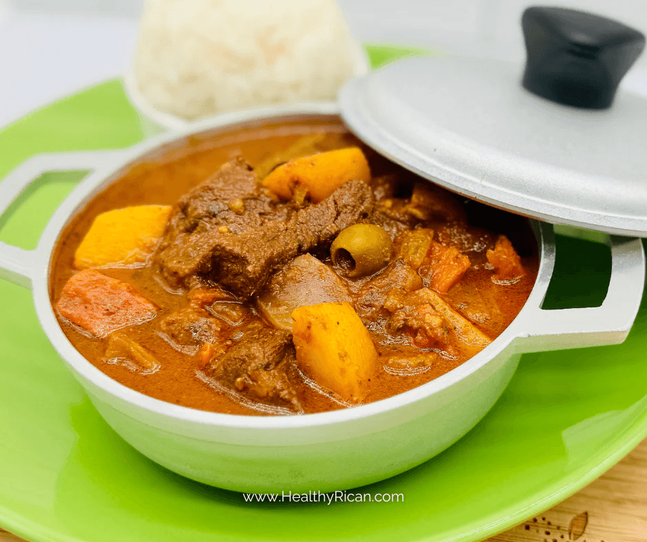 Puerto Rican beef stew with potatoes, carrots, and olives in rich brown sauce, served in a small pot.