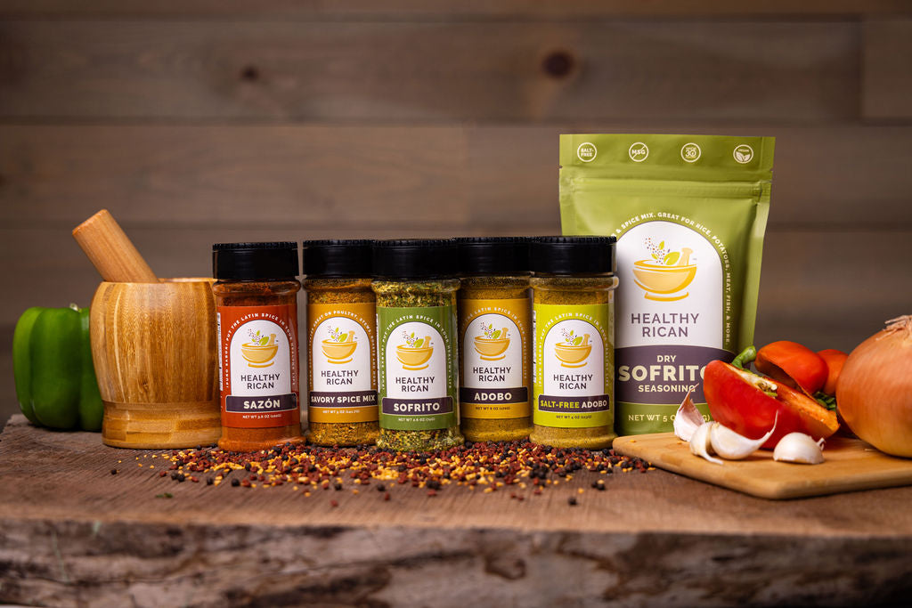 Healthy Rican seasoning collection featuring Sazón, Savory Spice Mix, Sofrito, Adobo, Salt-Free Adobo, and Dry Sofrito with fresh peppers, garlic, and onions.