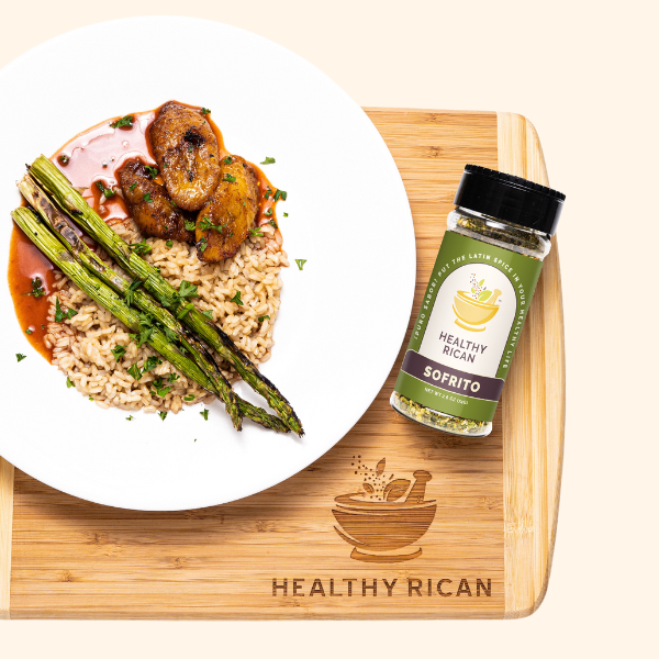 Healthy Rican Sofrito seasoning bottle beside a plated meal of rice, roasted chicken, and asparagus.