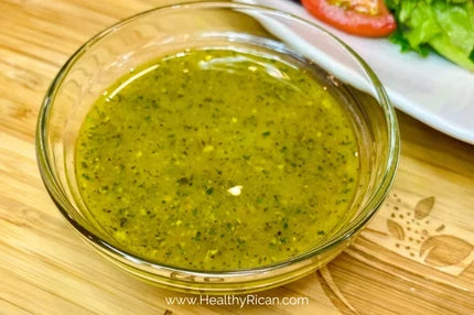 Healthy salad dressing made with fresh herbs and seasonings, served in a glass bowl beside a crisp green salad.