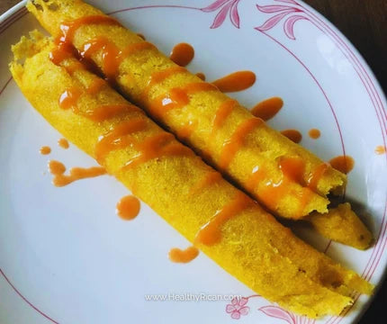 Puerto Rican cuisine featuring traditional pasteles served on a plate and topped with hot sauce.