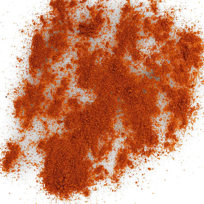 Loose Healthy Rican Sazón seasoning scattered on a white surface with rich orange-red Puerto Rican spices.