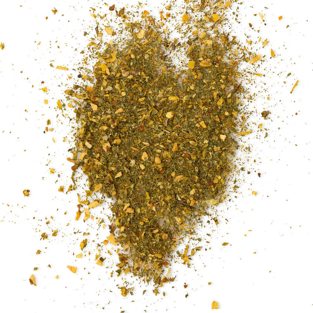Loose Healthy Rican Sofrito seasoning scattered on a white surface with dried herbs and Puerto Rican spices.